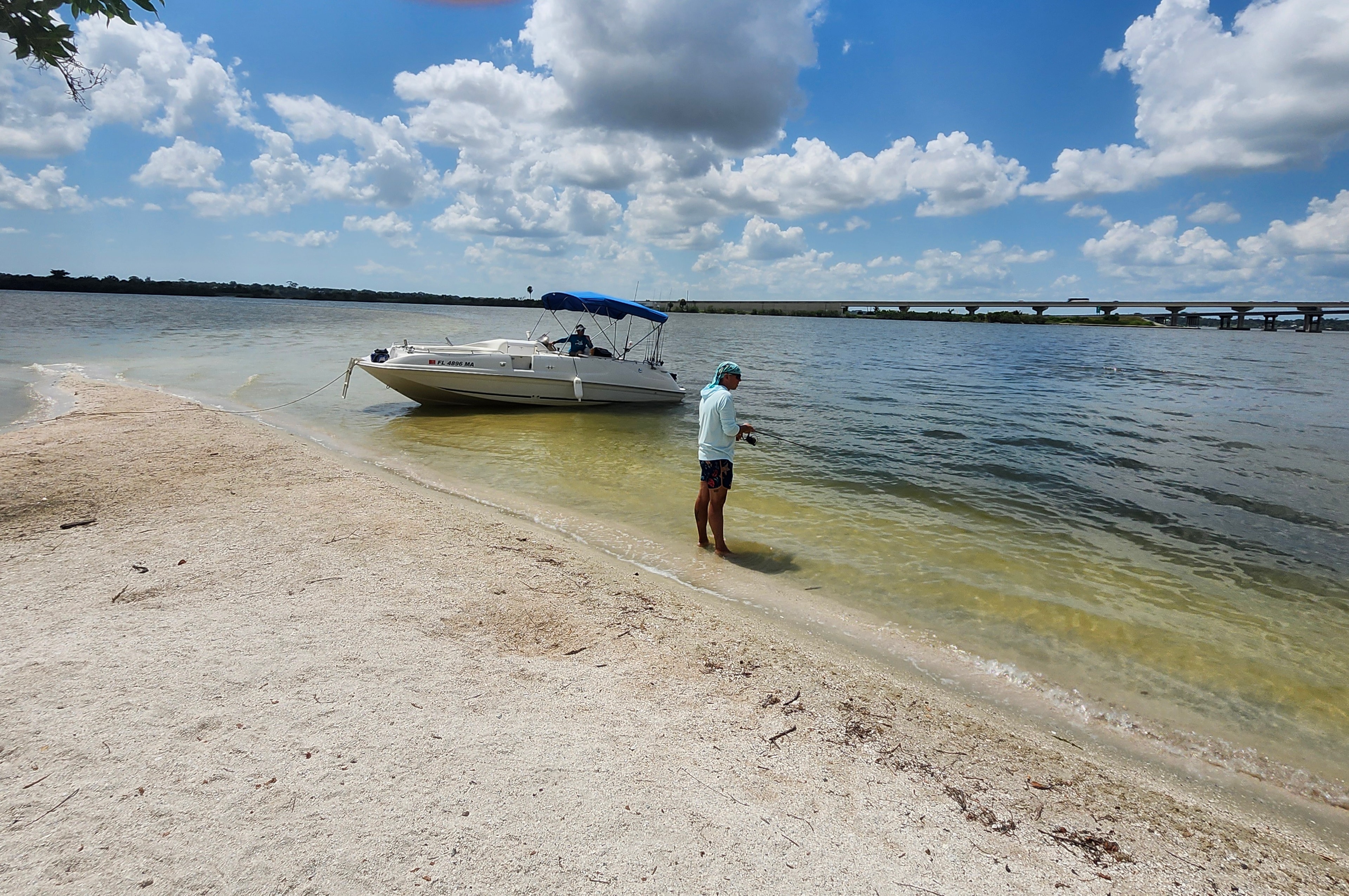 Guest fishing from the sandy shoreline beside Captain Pete's boat on the Indian River Lagoon